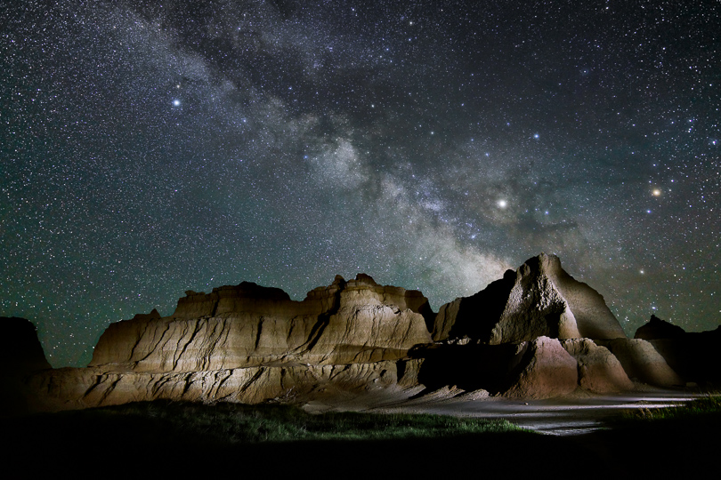 The Milky Way over the Badlands. Nearly all of my night sky photos are done in two pieces. The sky was exposed using a tracking mount to render the stars as sharp dots rather than streaks. The foreground was exposed with the tracking mount turned off and I light painted the hills using an LED flashlight. The two pieces are then combined in Photoshop.