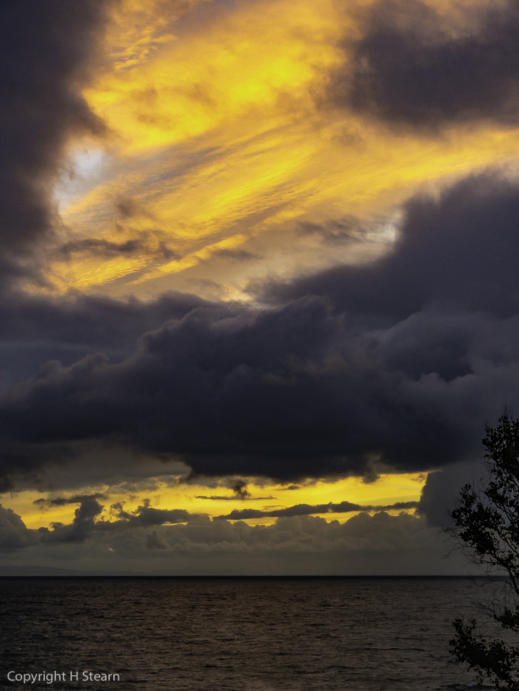 Brilliantly lit cirrus clouds appear between dense cumulus layers