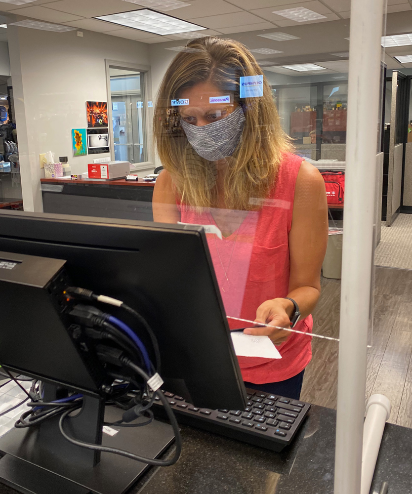 Meredith Reinker, partner at Roberts checks a customer out behind the counter shield