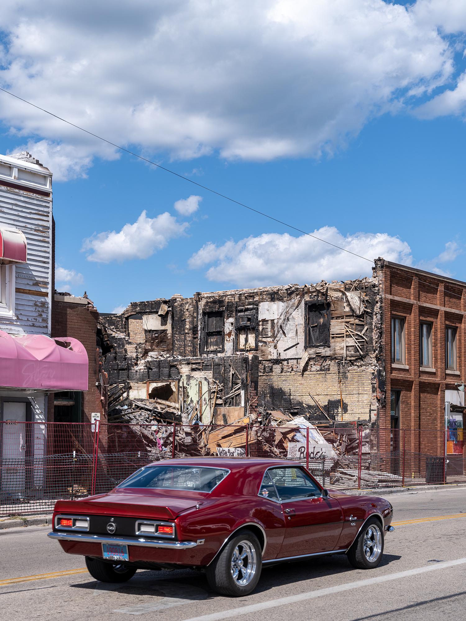 A Car Drives Past a Burned-Out Camera Store