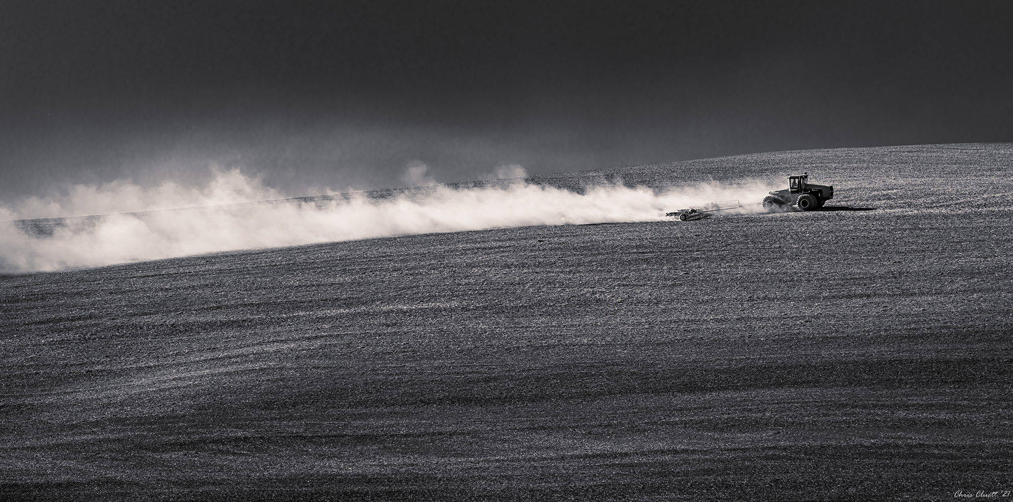 A long plume of dust follows this tractor rig and the farmer in his air-conditioned cab.