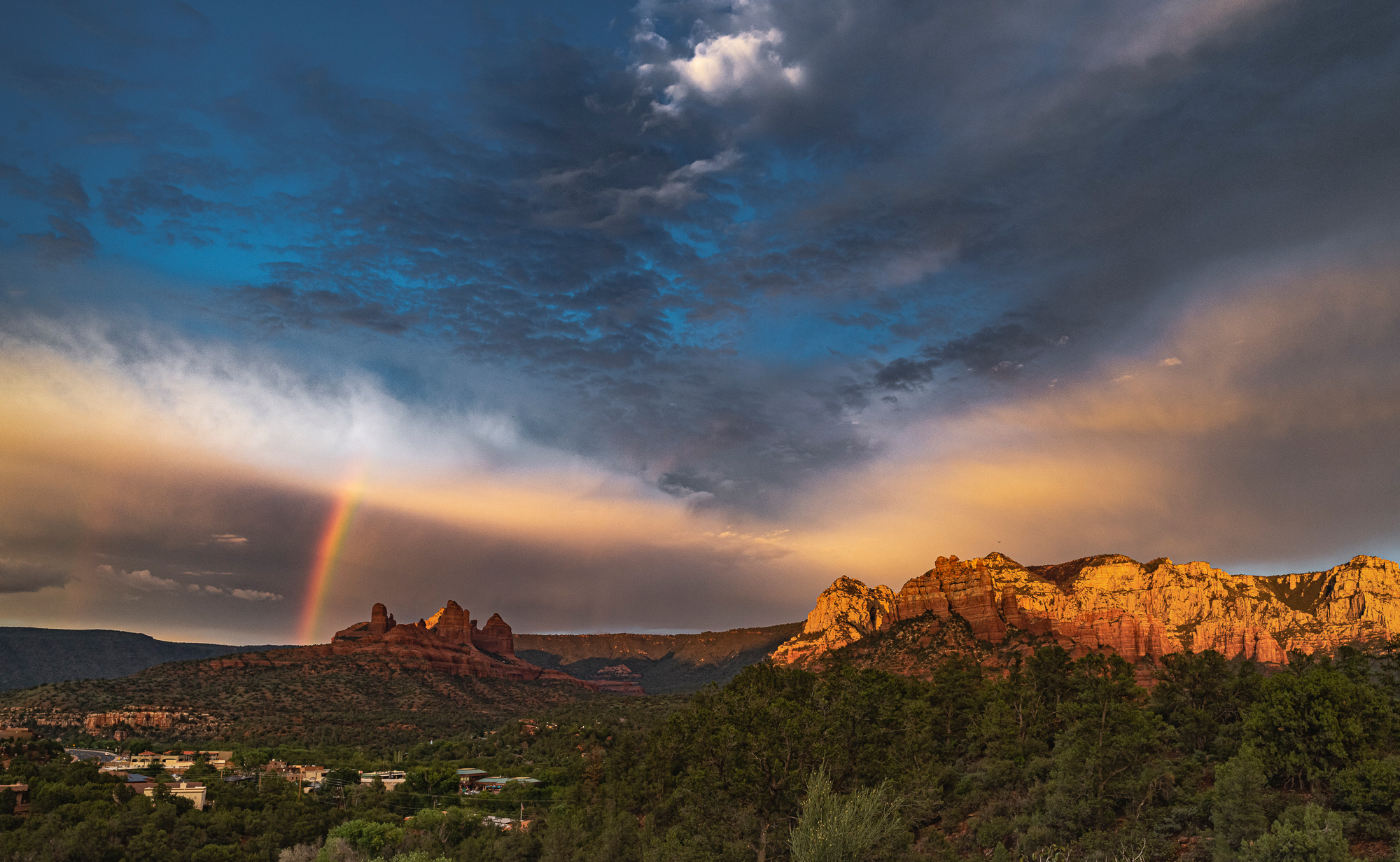 The edge of retreating storm shows a rainbow and scattered light