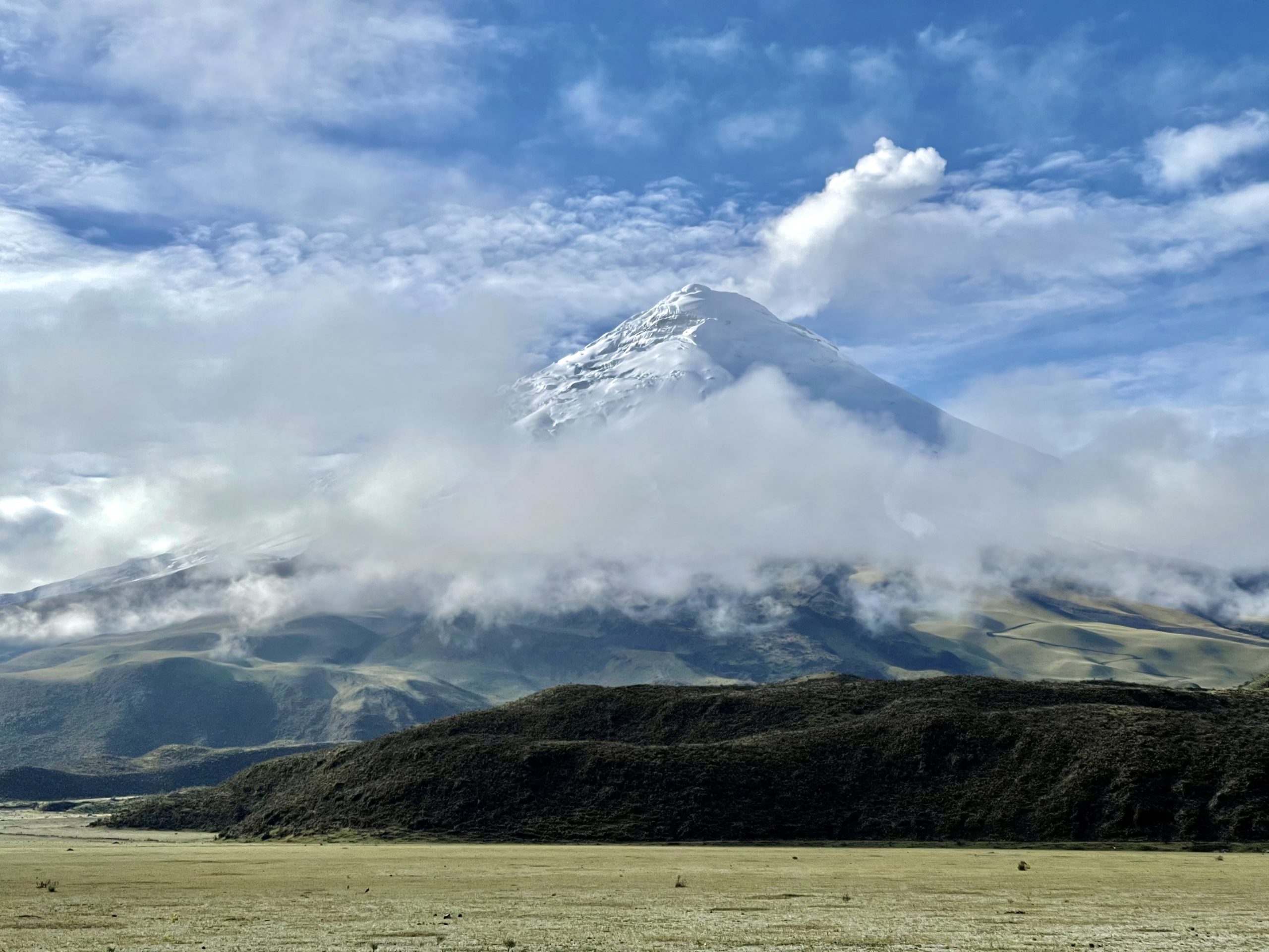 Tall mountain peak standing tall through clouds in the Andes, snowy and serene