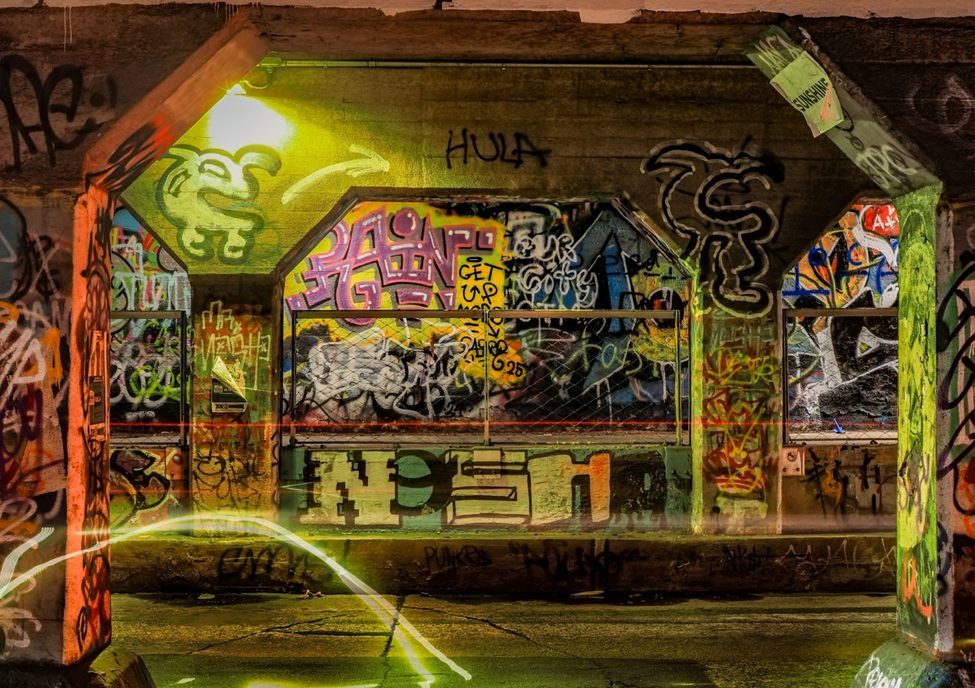 Vivid urban graffiti scene captured using the OM System OM-3 with Built-in ND filter for long-exposure light painting. The colorful street art, illuminated by artificial lighting, highlights the camera’s computational photography capabilities, making it a powerful tool for creative night photography.