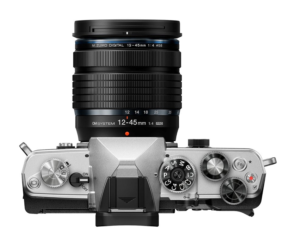 Top view of OM System mirrorless camera with M.Zuiko Digital 12-45mm f/4 PRO lens, showcasing dials and controls for professional photography