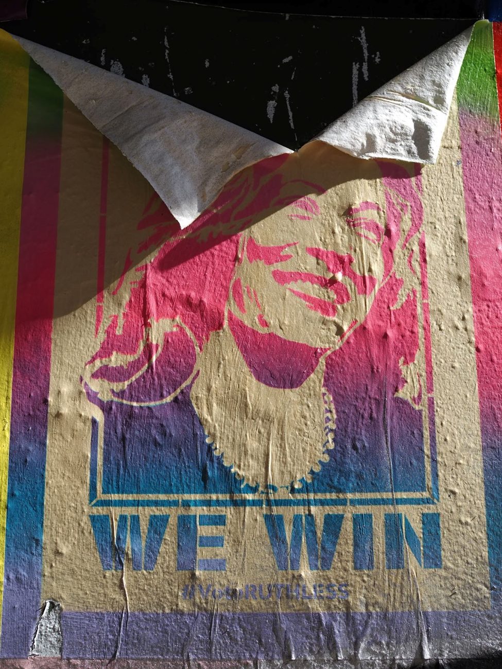 Street photography shot of a peeling urban art poster, revealing layered textures and bold colors. The image captures natural light, shadows, and depth, highlighting the decay and resilience of street art. (ISO 100, 25mm, f/5.0, 1/250 sec)