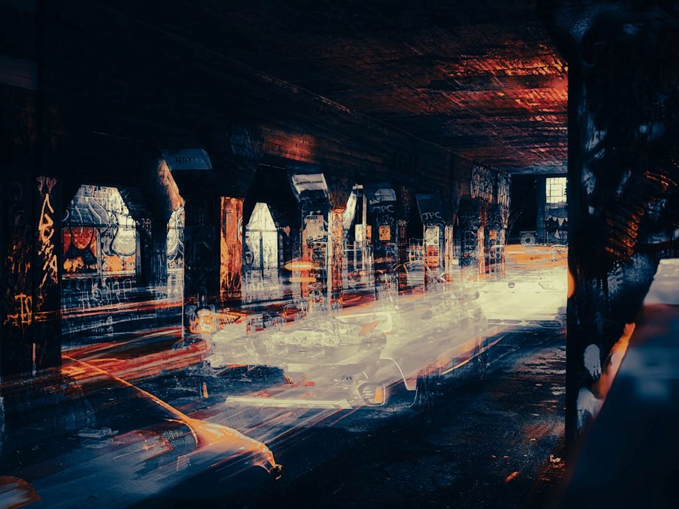 Long exposure photograph of cars moving through a graffiti-covered urban tunnel, showcasing the OM System OM-3's Live ND feature. The computational photography effect creates artistic light trails, demonstrating the camera’s creative potential for street and low-light photography.