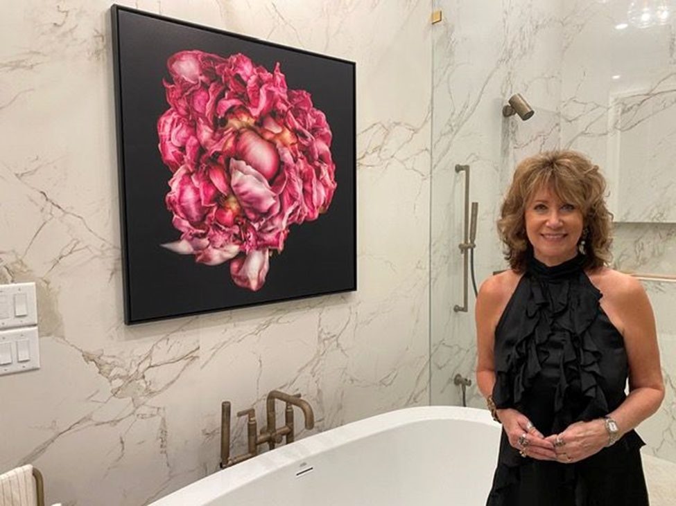 Adrienne Anbinder standing beside her large pink floral digital mixed media artwork, showcasing her unique style and creative vision.