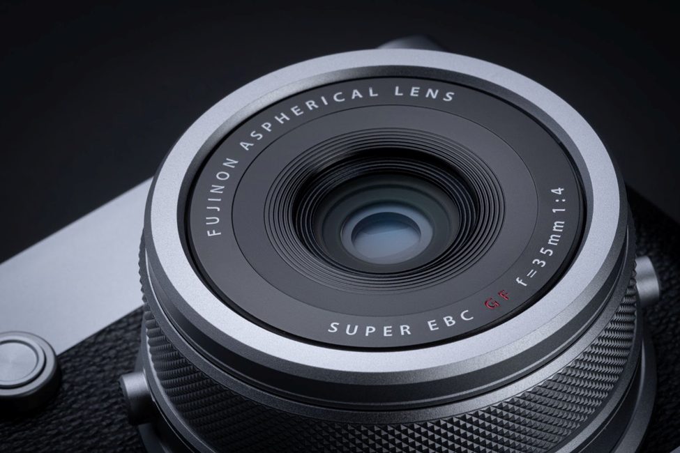 Close-up of the Fujinon GF 35mm f/1.4 lens on the Fujifilm GFX100RF, highlighting its aspherical glass elements and Super EBC coating. This premium medium format lens delivers exceptional sharpness and bokeh for professional photography.
