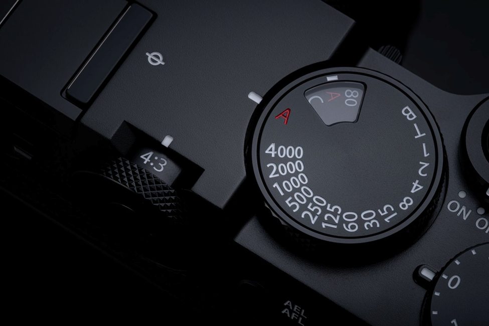 Detailed view of the Fujifilm GFX100RF’s top dials, featuring the classic shutter speed control and aspect ratio switch. The sleek black design emphasizes Fujifilm’s signature blend of retro aesthetics and modern functionality for professional photographers.