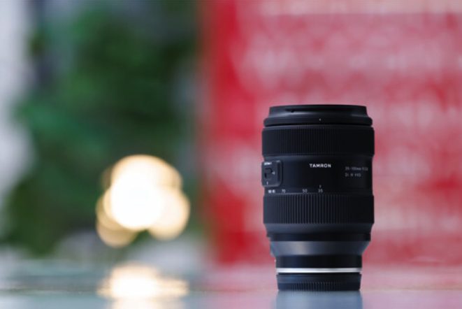 Tamron 35-100mm f/2.8 lens standing on a table with blurred background lights