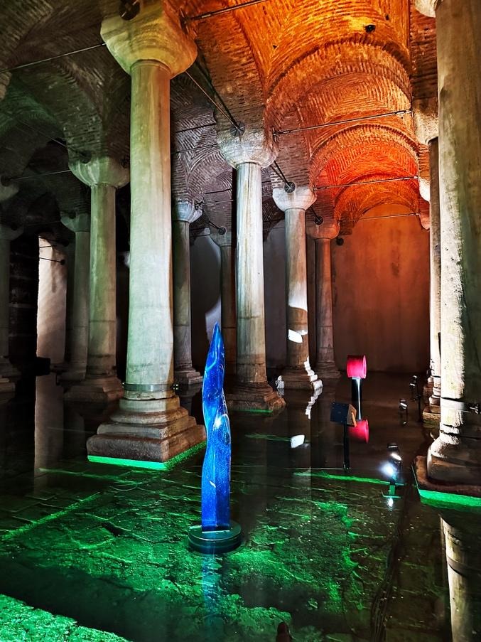 Basilica Cistern columns in Istanbul with blue sculpture and green-lit reflections