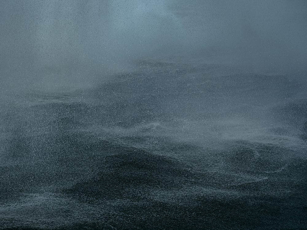 Misty dark water at Seljalandsfoss Waterfall, Iceland, with spray and layered textures.