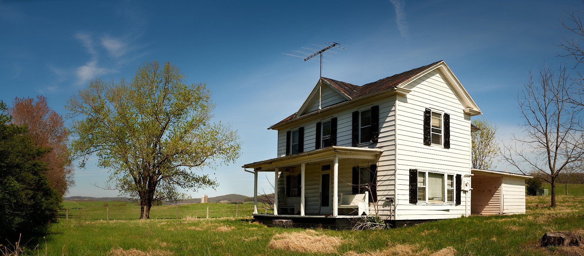 White farmhouse in open field under blue sky