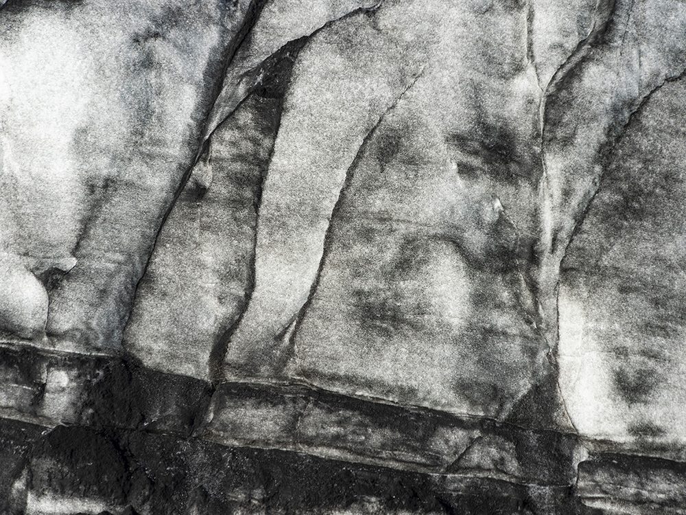 Abstract glacier surface at Sólheimajökull, Iceland, with cracked ice and stone-like textures.