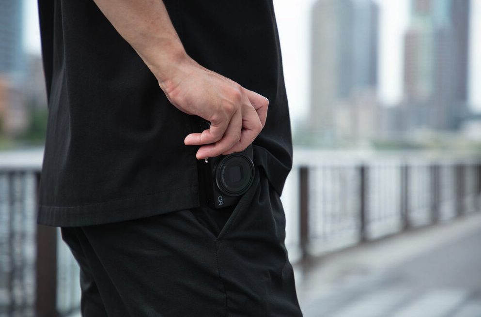 Ricoh GR IV camera partially in pocket while walking outdoors