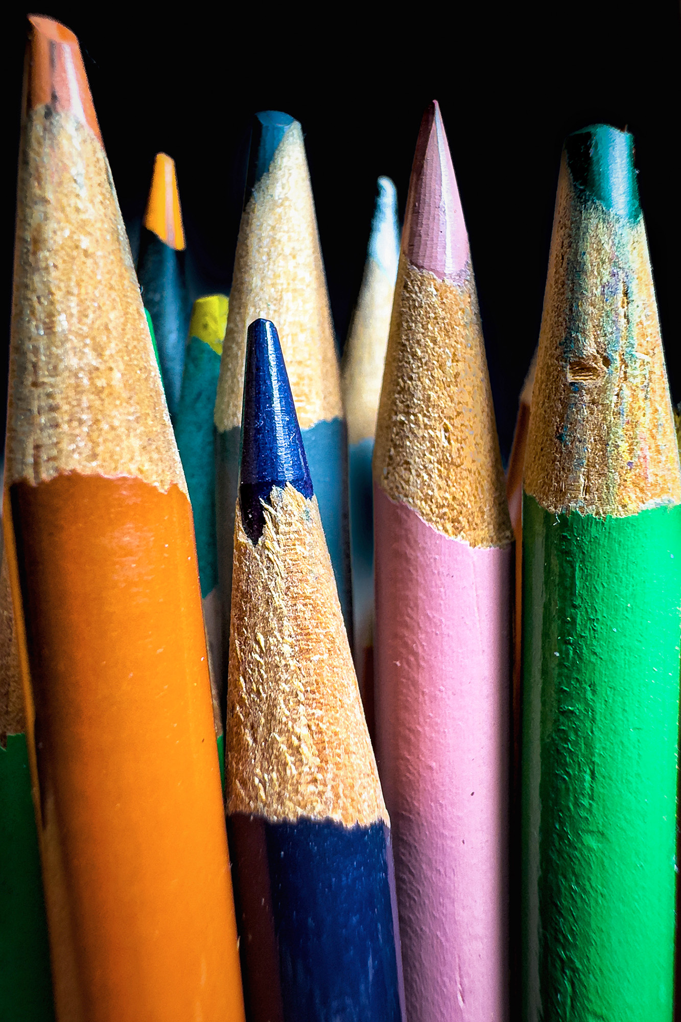 Close-up macro photo of colored pencil tips against a dark background