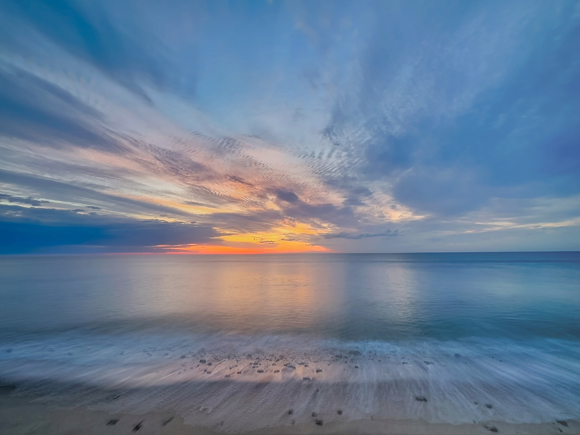 Long exposure seascape with soft waves and colorful sunset sky