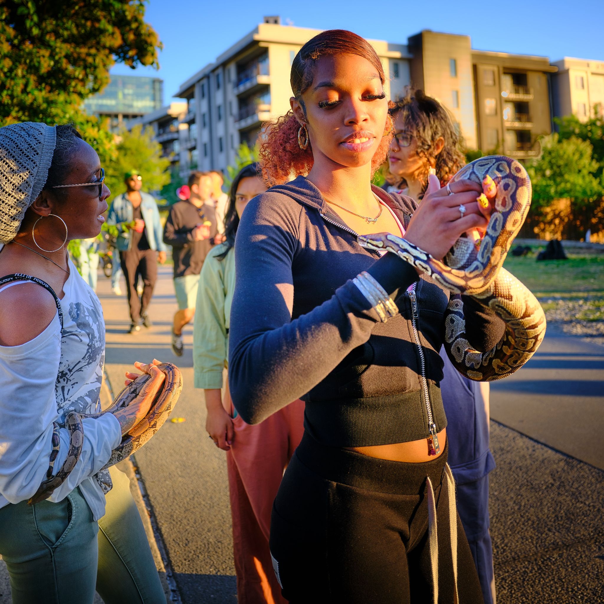 Woman holding a snake at a public gathering, showcasing GFX100RF subject detail
