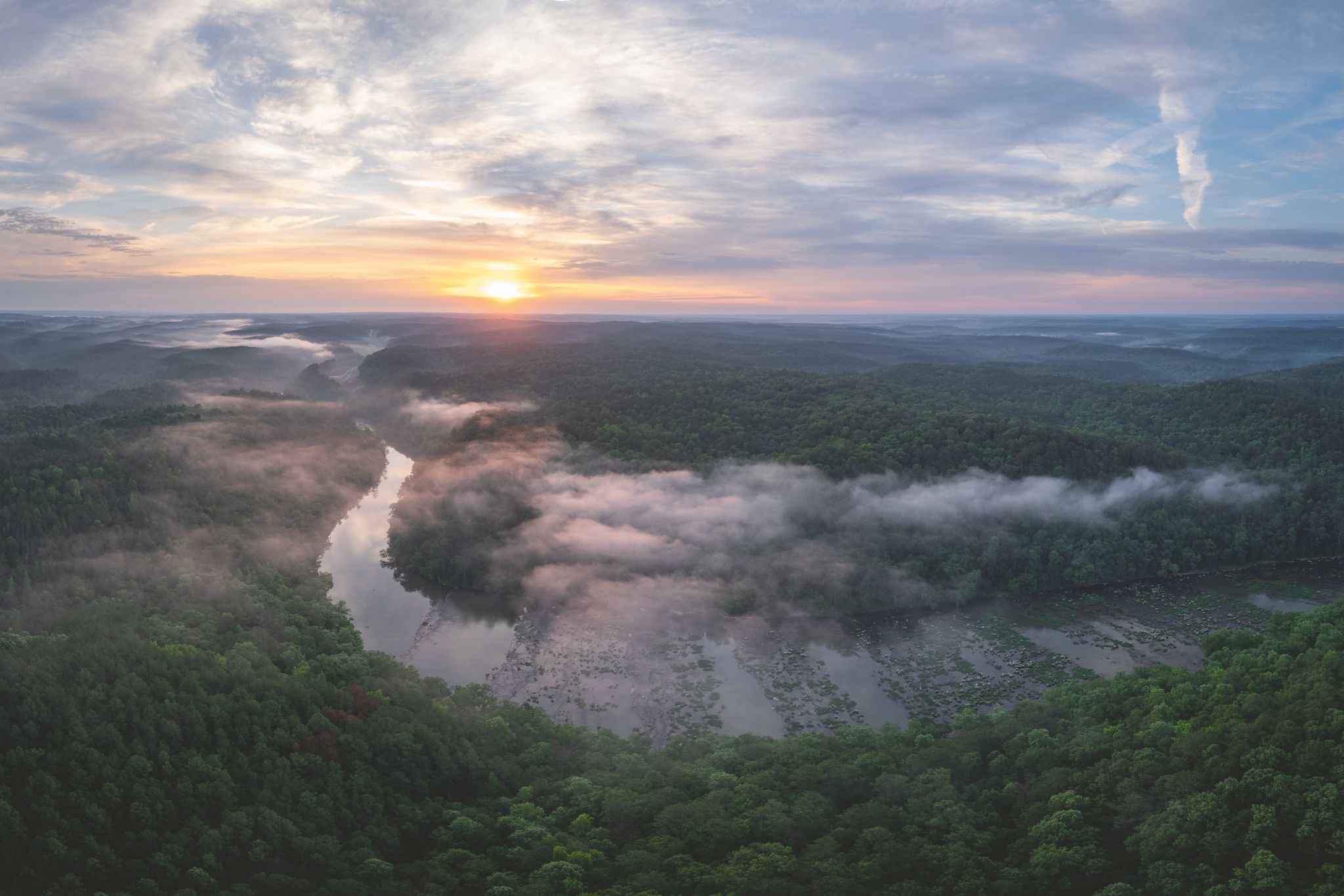 Aerial view of a winding river and forest at sunrise in the American Southeast