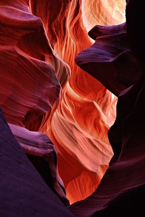 Curving sandstone walls glowing with red and orange reflected light