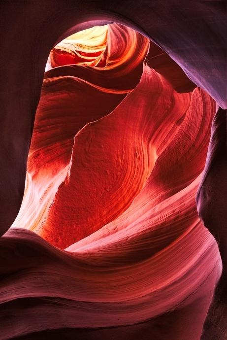 Smooth red sandstone arch illuminated inside Antelope Canyon