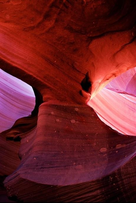 Hourglass-shaped sandstone formation lit by soft reflected light