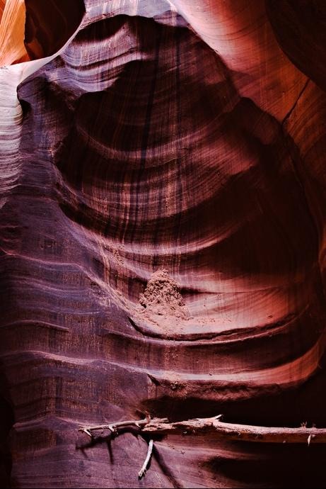 Textured sandstone wall with layered shadows and fallen branch