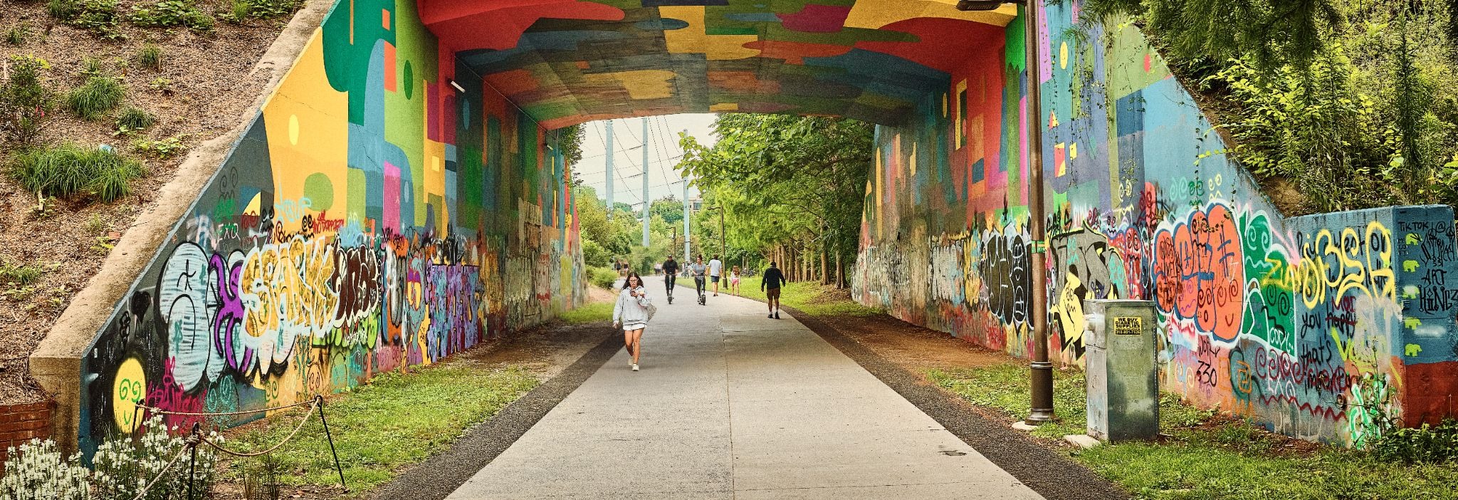 Pedestrians walking through a graffiti-covered tunnel captured with the GFX100RF