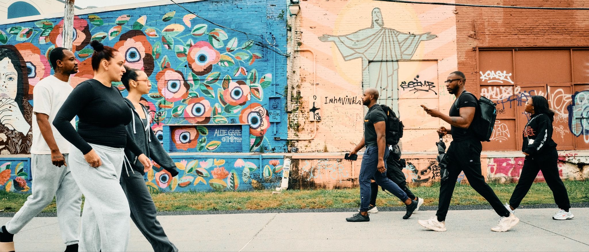People passing a vibrant mural wall, showing GFX100RF street photography rendering