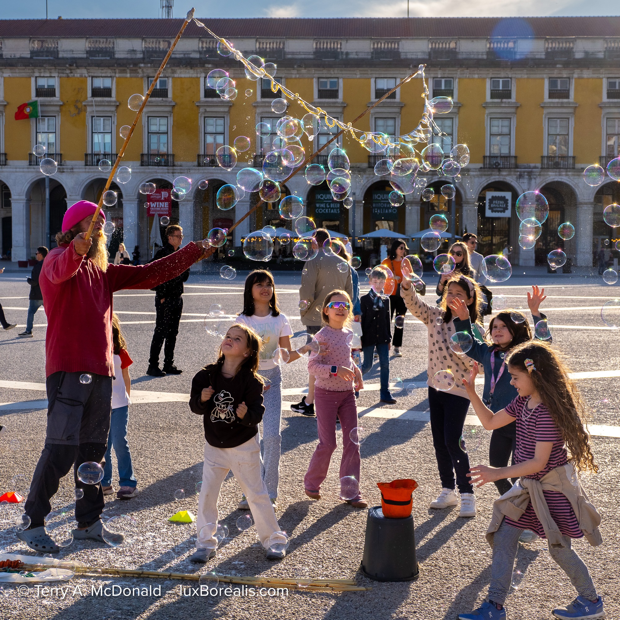 Street performer creating giant bubbles for children in Praça do Comércio