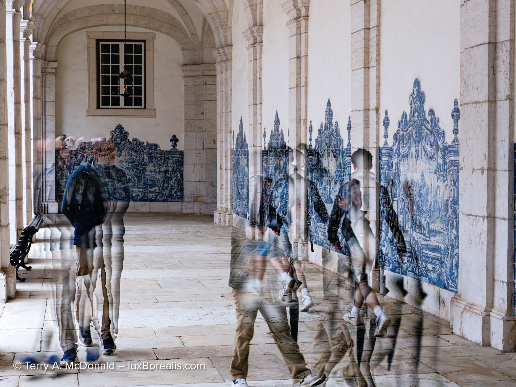 Blurred visitors walking through a tiled cloister in Lisbon monastery