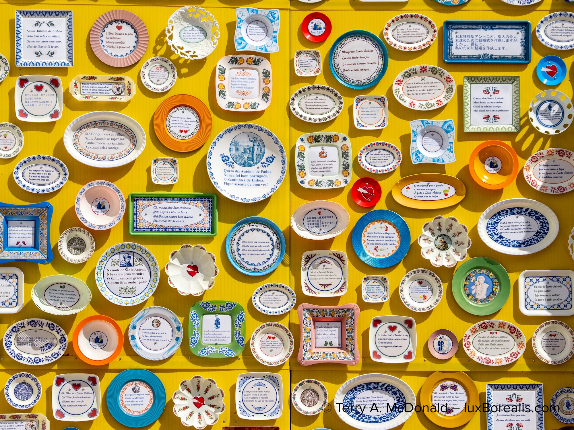 Decorative ceramic plates displayed on a bright yellow wall in Lisbon