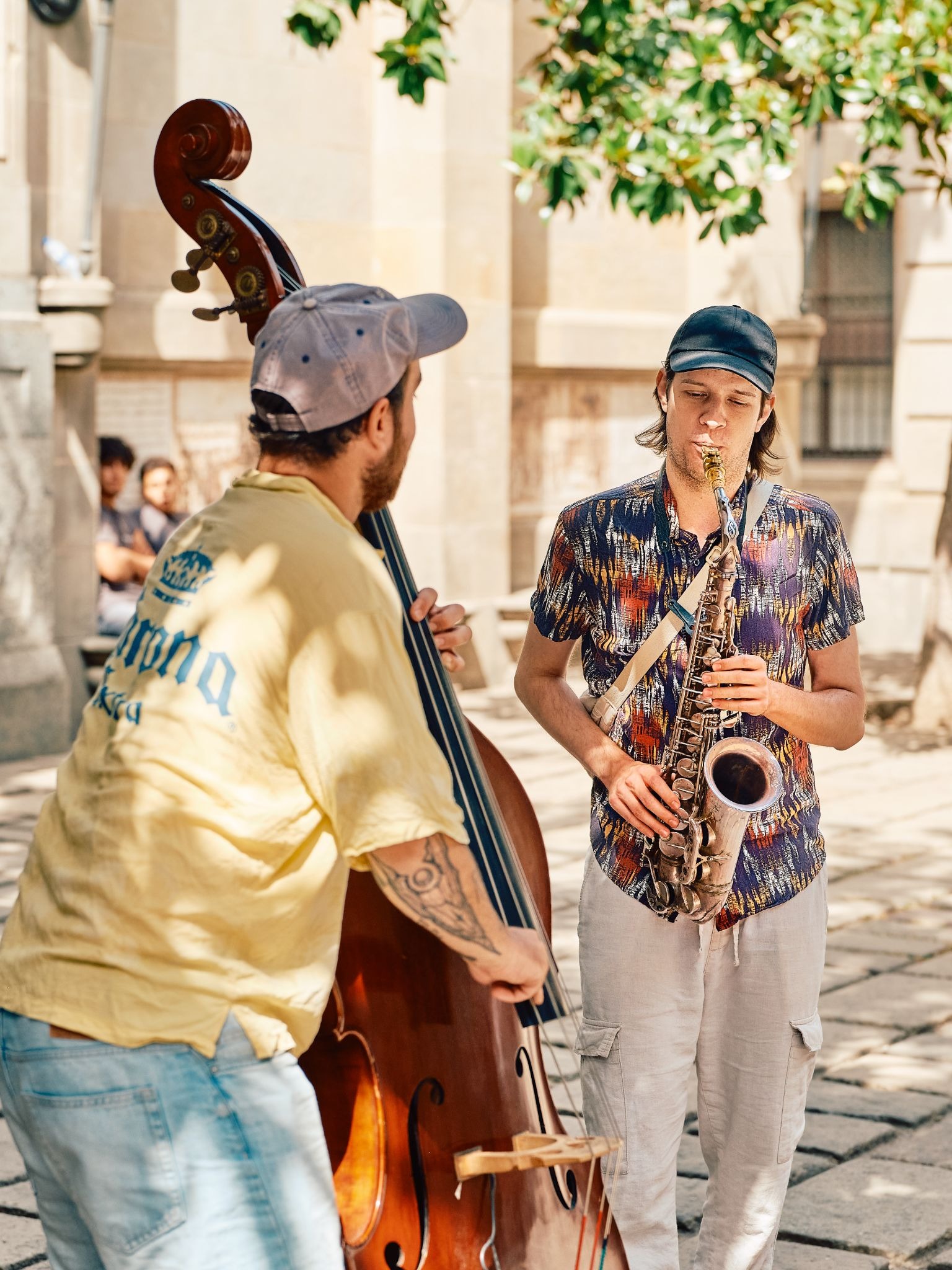 Street musicians performing with a saxophone and double bass.