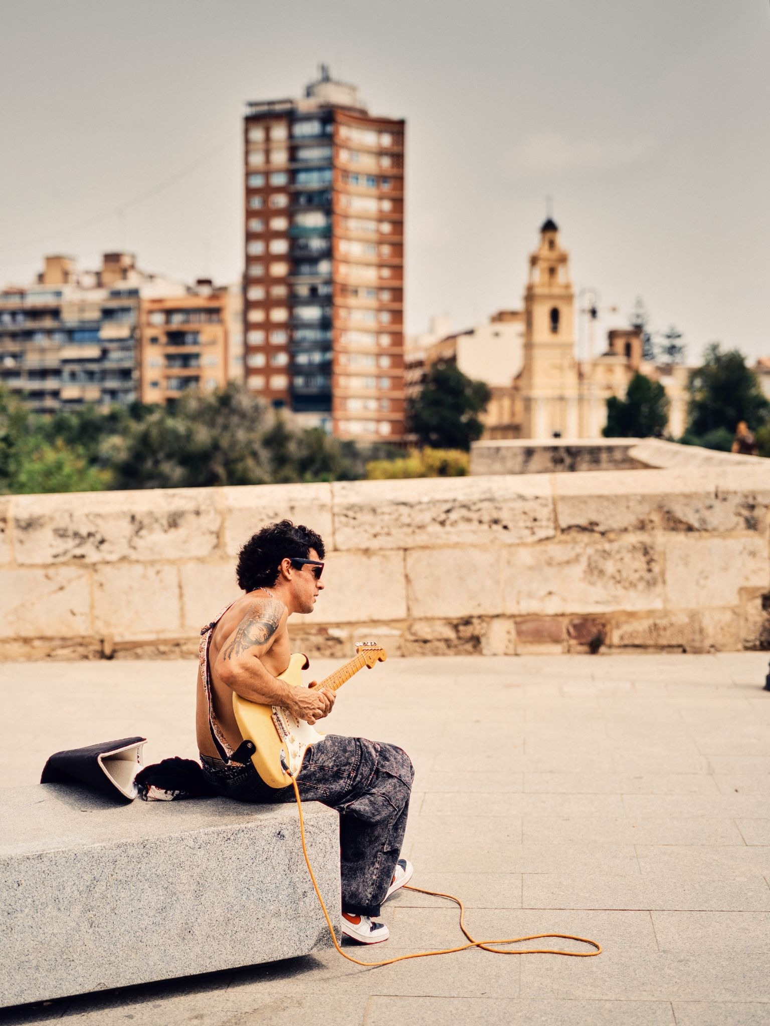 Man playing an electric guitar in a city plaza.