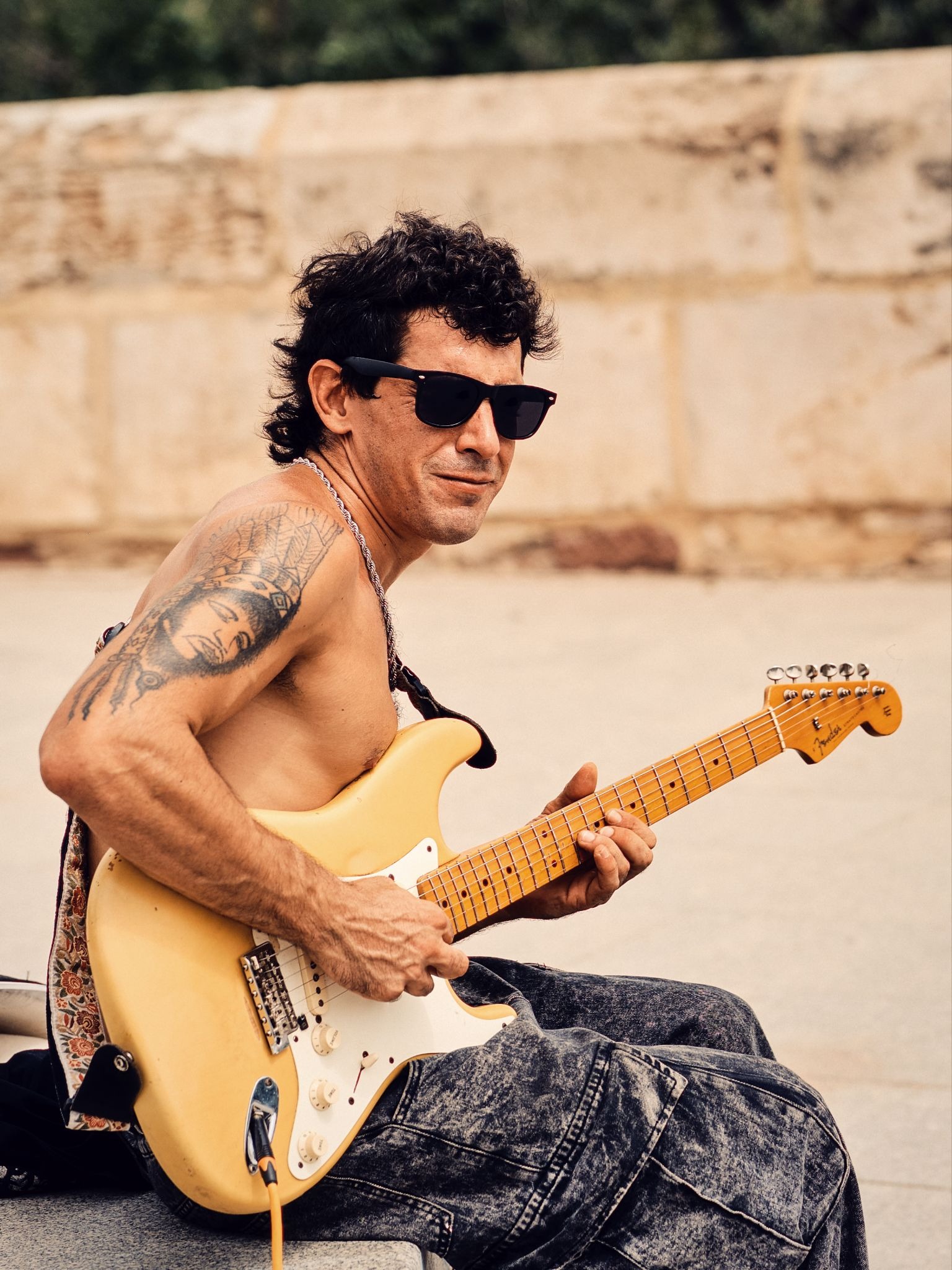 Close-up portrait of a street guitarist wearing sunglasses.