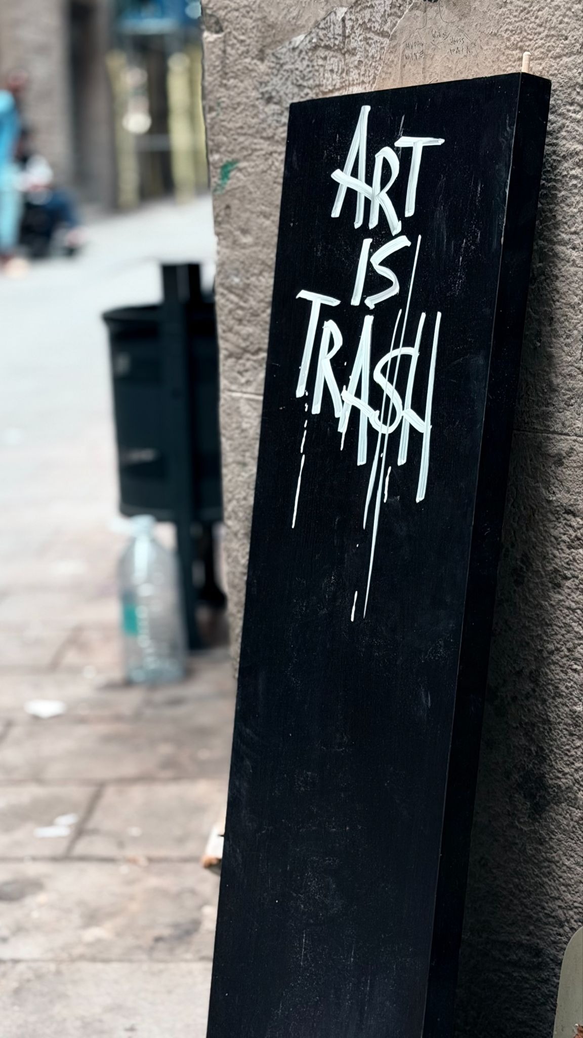 Black sign with the words "Art Is Trash" painted in white.