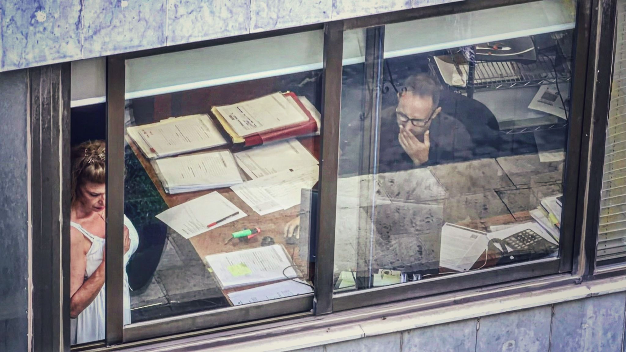 People working inside an office viewed through a window.