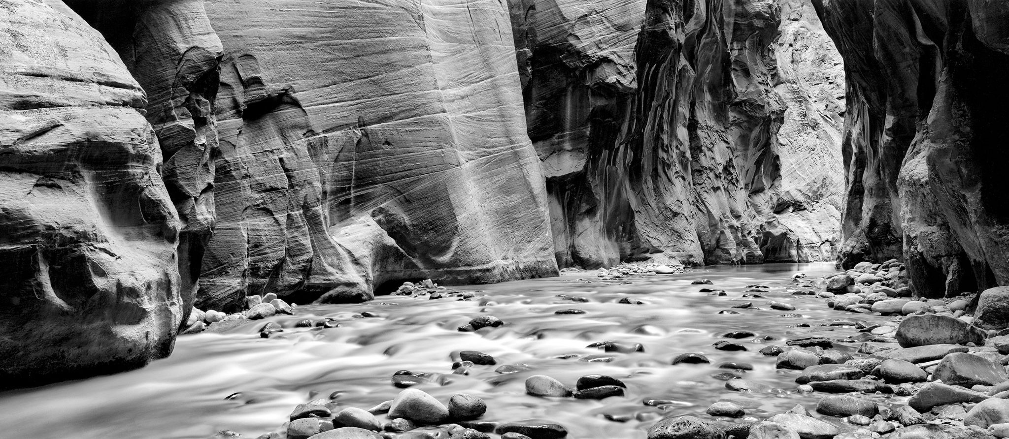 Smooth river flowing through a narrow black-and-white sandstone canyon