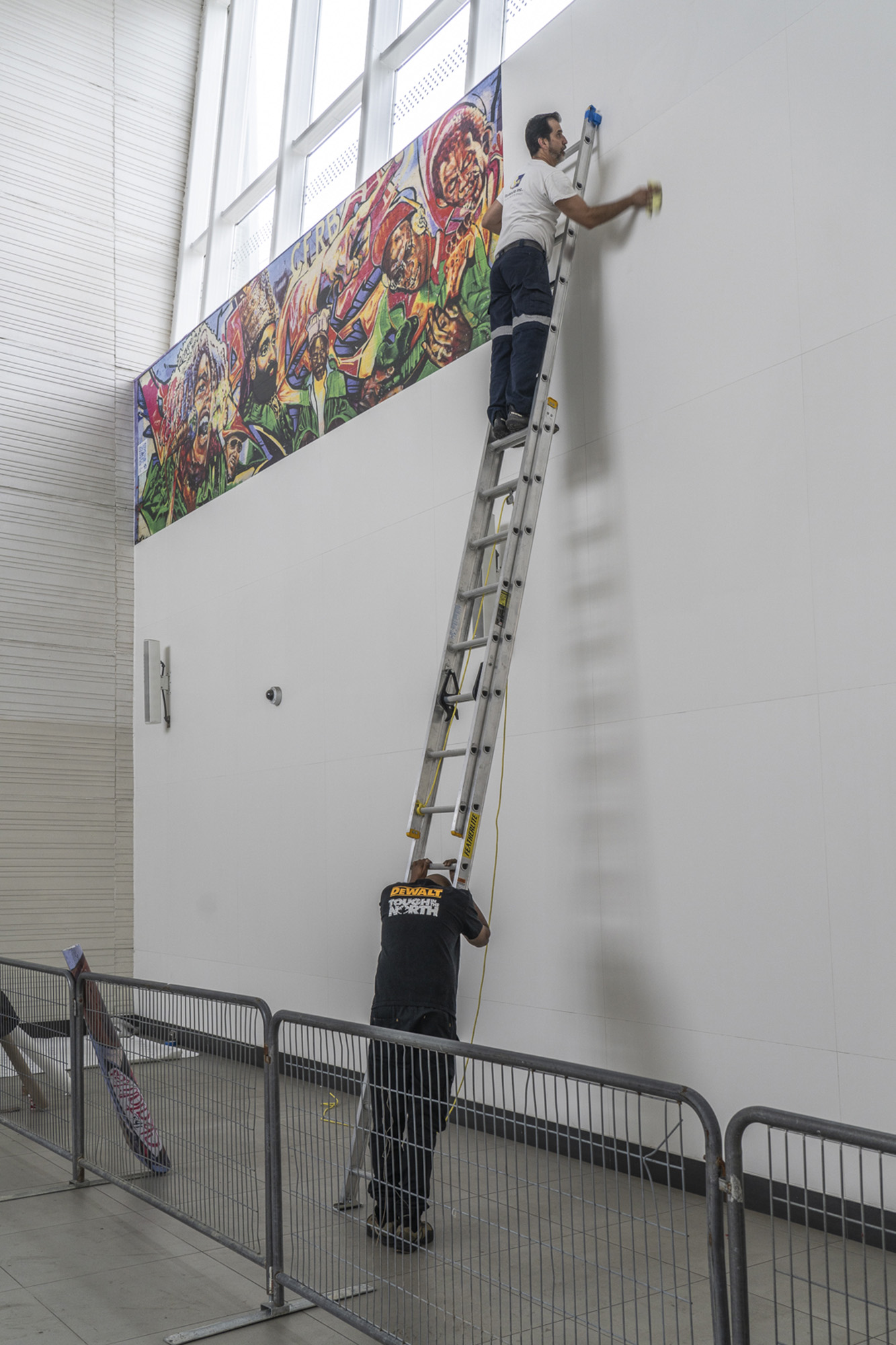 Installers mounting the Reggae mural panels on the station wall