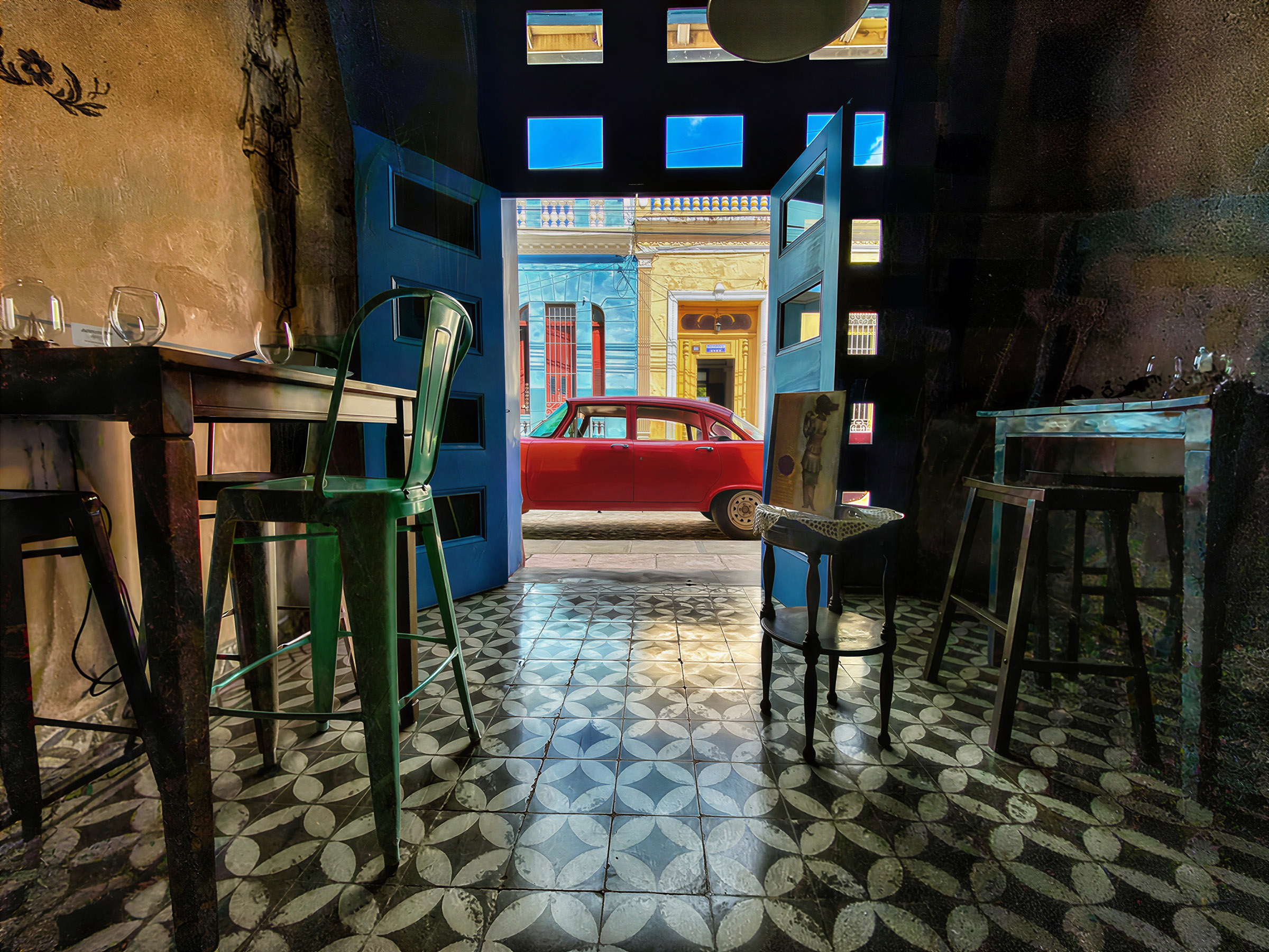 Red vintage car passing a colorful building in Trinidad, Cuba.
