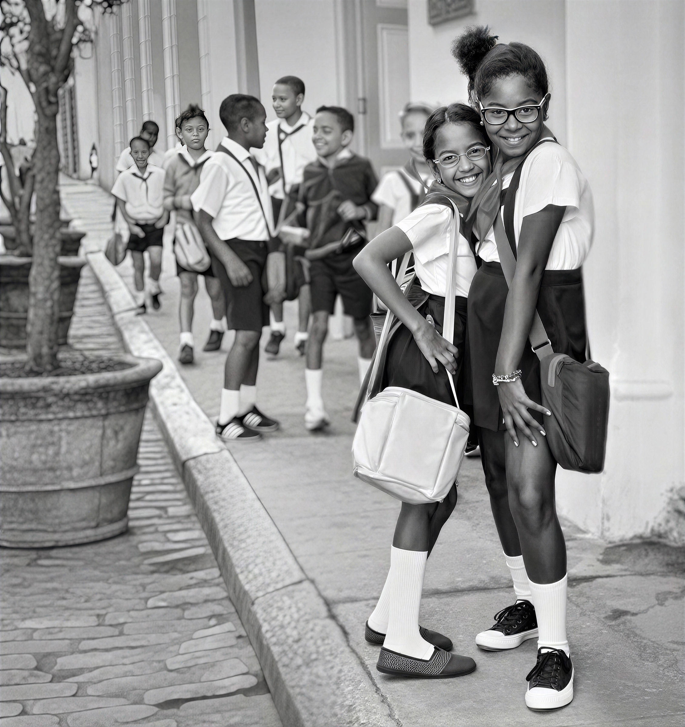 Two schoolgirls standing together on a street in Old Havana, with other students in the background.
