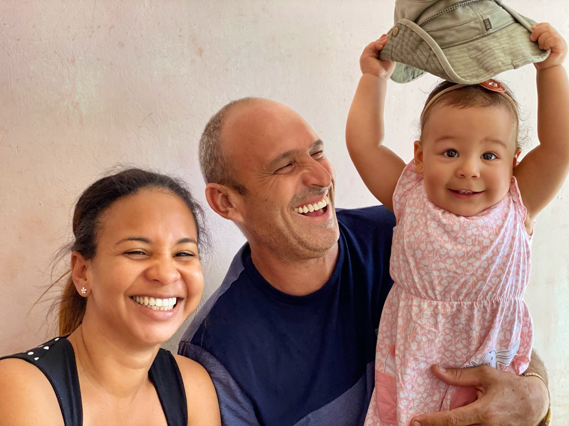 Vivian, Miguel, and their daughter Amber smiling together at home outside Havana.