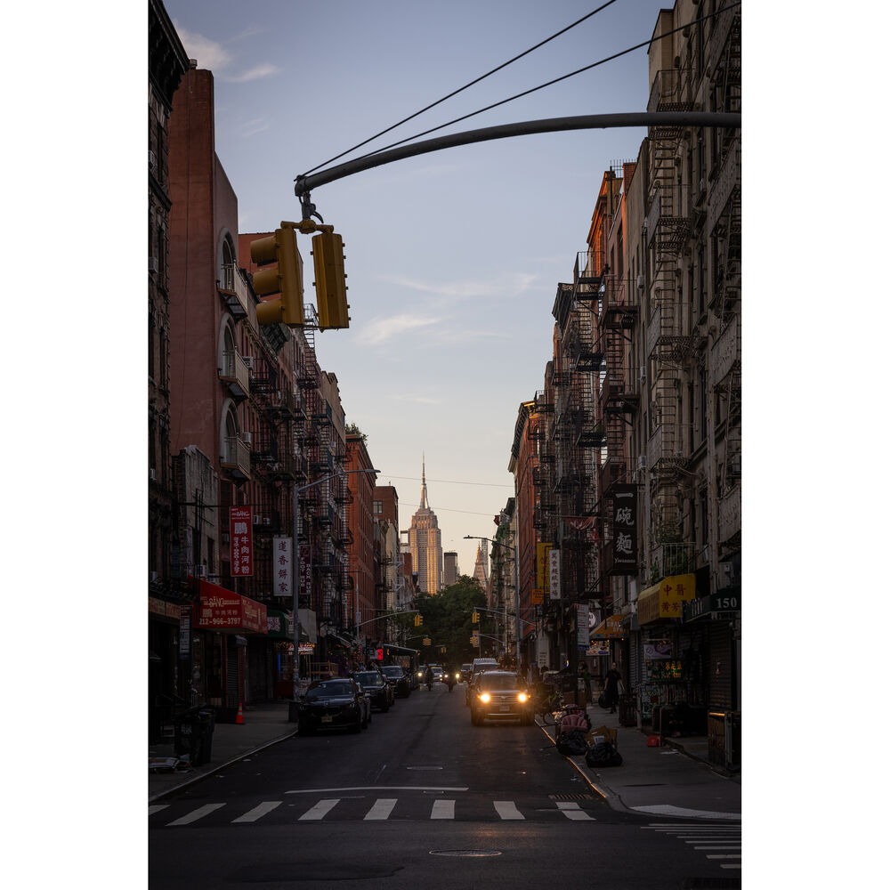 City street lined with buildings and the Empire State Building in the distance.