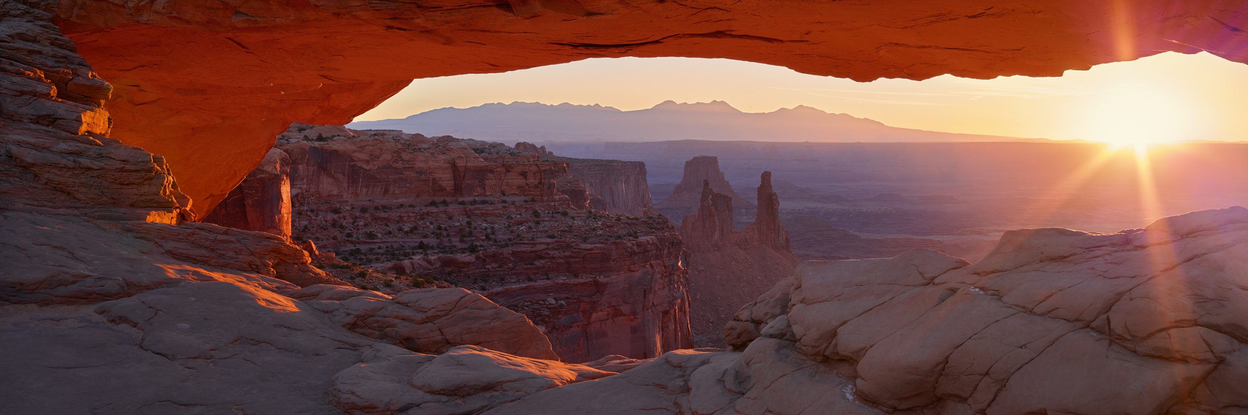 Sunlight shining through Mesa Arch over the Canyonlands landscape