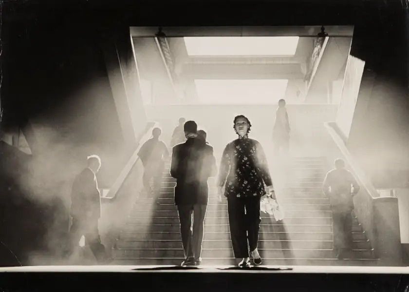 People walking on a staircase through mist and light in Fan Ho's Smoky World, 1959