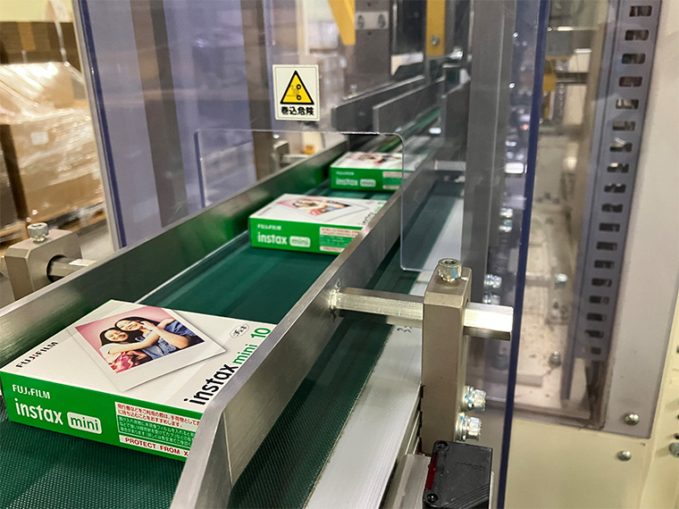 Fujifilm Instax Mini instant film boxes moving along a factory conveyor belt