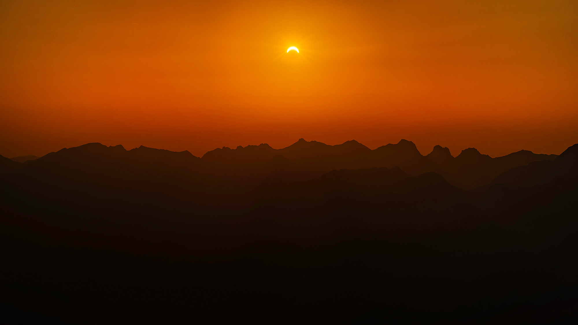 Crescent Sun above the mountains at sunset