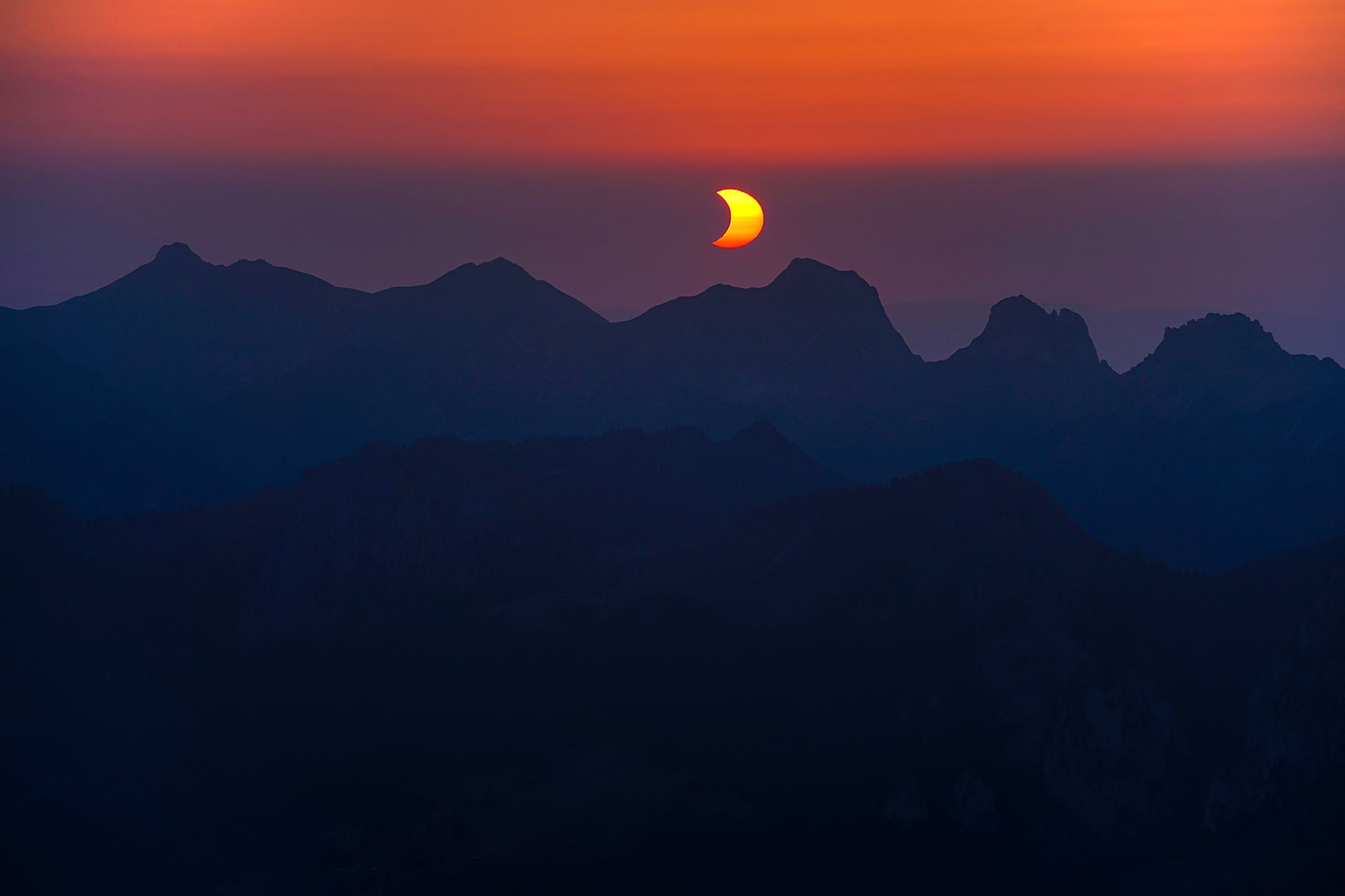 Partial solar eclipse over the Swiss Alps at sunset