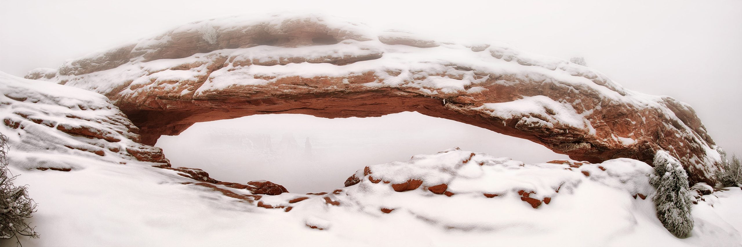 Mesa Arch covered in snow and dense fog at Canyonlands National Park, Utah